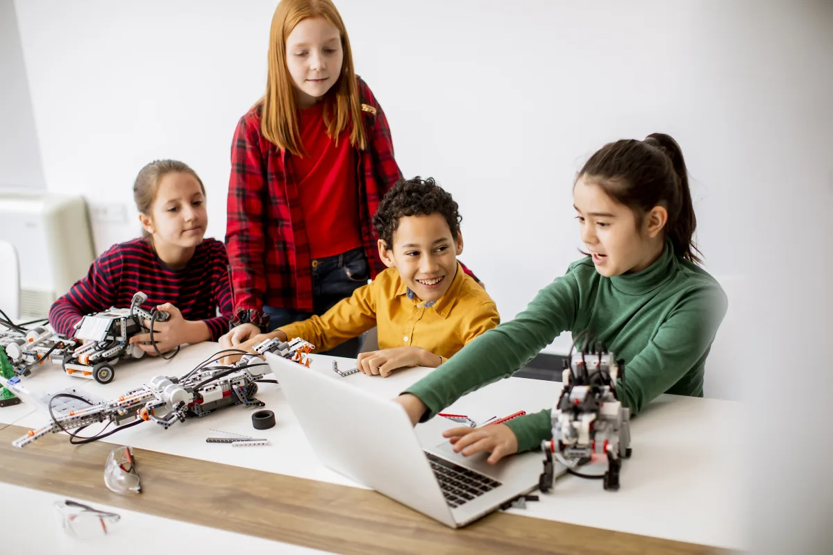 Happy kids programming electric toys and robots at robotics clas